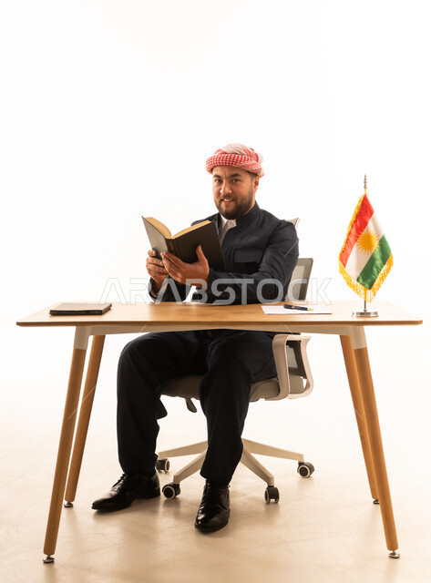 رجل باللباس الكوردي التقليدي يقرأ على المكتب