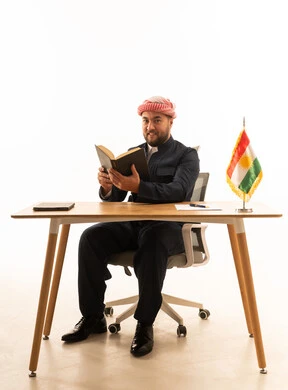 Kurdish Man in Traditional Attire Reading at Desk