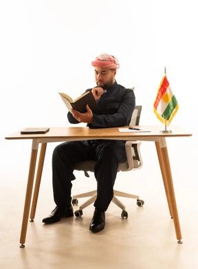 رجل كوردستاني يقرأ كتاباً خلف مكتبه