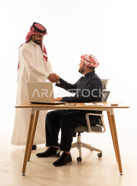 رجل سعودي وكردي يتصافحان خلف مكتب عمل