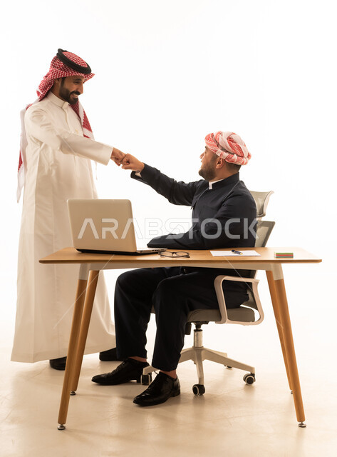 Saudi and Kurdish Businessmen Fist Bump at Office Desk