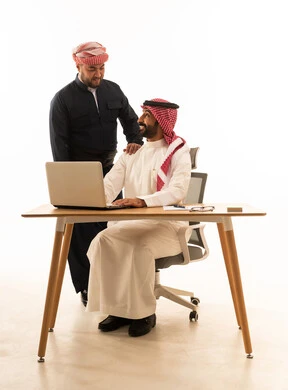 رجل أعمال سعودي وكردي يعملان على الحاسوب