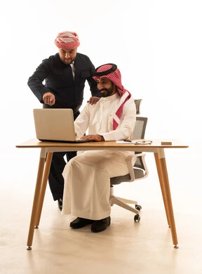رجل أعمال سعودي وكوردستاني يعملان على كمبيوتر محمول