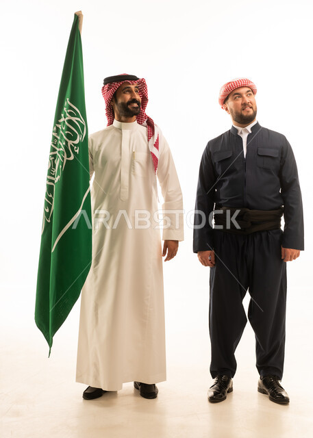 رجل سعودي وكردي بالزي التقليدي الرسمي مع العلم السعودي