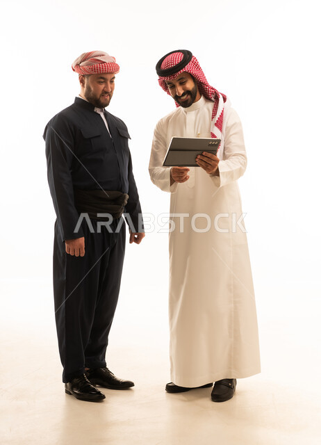 رجل سعودي وكردي يستخدمان جهاز لوحي بخلفية بيضاء