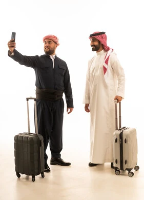 مسافر سعودي وكوردستاني مع حقائب سفر وخلفية بيضاء