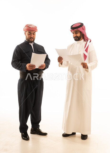 رجل سعودي وكردي يراجعان وثائق ورقية على خلفية بيضاء