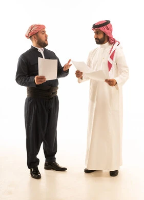 رجل سعودي وكردي يناقشان مستندات بخلفية بيضاء