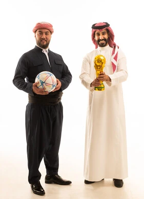 رجل سعودي وكردي مع كأس البطولة وكرة قدم