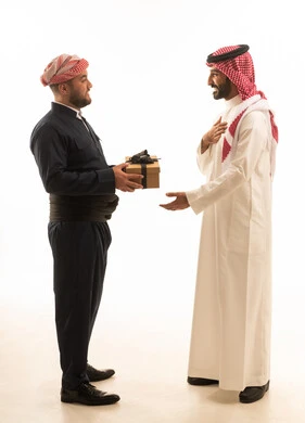 رجل سعودي وكردي يتبادلان الهدايا بخلفية بيضاء