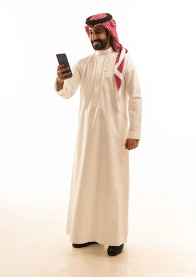 رجل سعودي بالثوب يستخدم الهاتف الذكي بخلفية بيضاء
