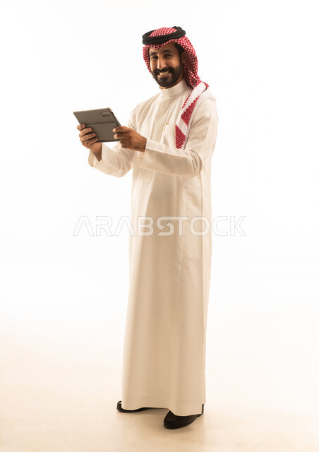 رجل سعودي يحمل جهاز لوحي بخلفية بيضاء