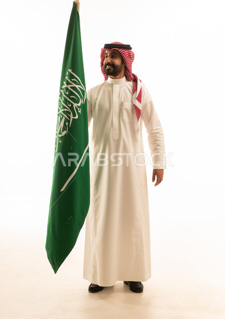 رجل سعودي يحمل العلم الوطني على خلفية بيضاء
