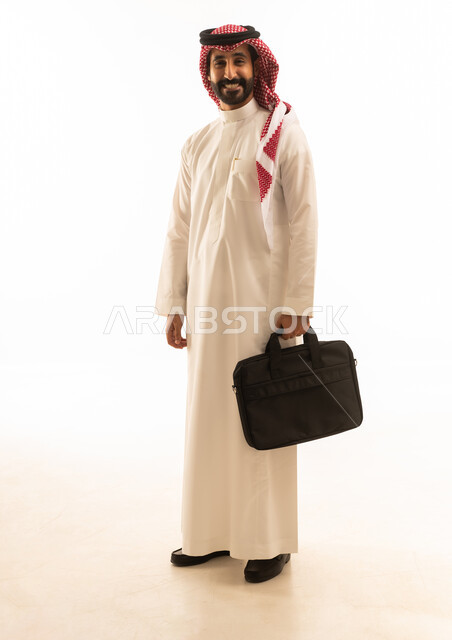 رجل أعمال سعودي بالثوب التقليدي يحمل حقيبة محمول