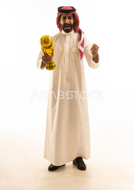 رجل سعودي يحمل كأس كرة قدم ذهبي بخلفية بيضاء