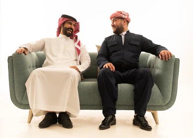 رجل سعودي وكردي يضحكان على الأريكة في الاستوديو