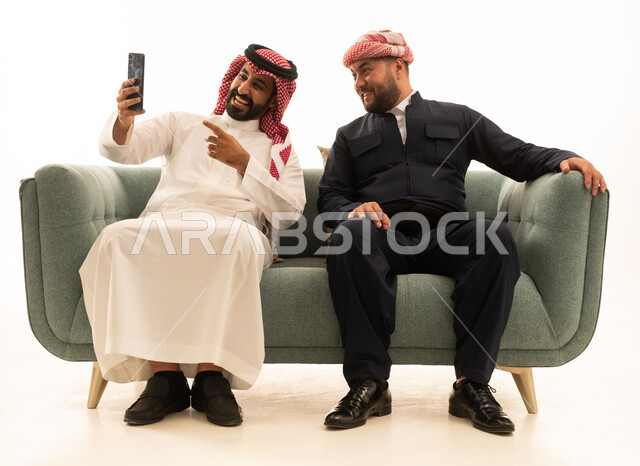 رجل سعودي وكردي يلتقطان صورة سيلفي على أريكة