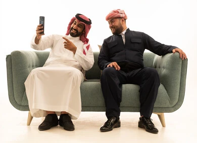 رجل سعودي وكردي يلتقطان صورة سيلفي على أريكة