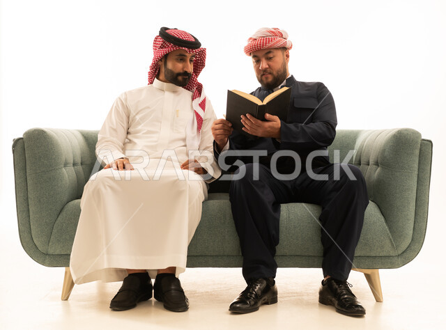 رجل سعودي وكردي يقرآن كتابا على أريكة خضراء