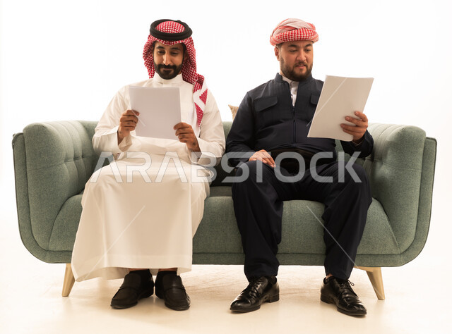 Saudi and Kurdish Men Reading Documents on Sofa