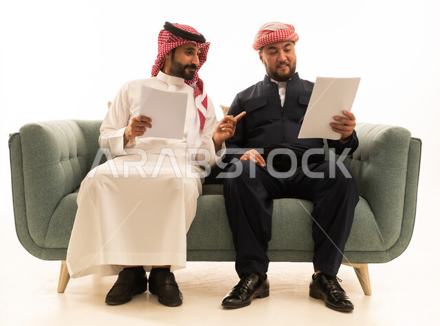 رجل سعودي وكردي يناقشان وثائق على الأريكة