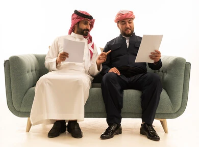رجل سعودي وكردي يناقشان وثائق على الأريكة
