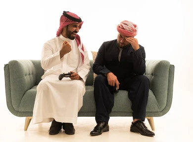 رجل سعودي وكوردستاني يلعبان ألعاب الفيديو على الأريكة