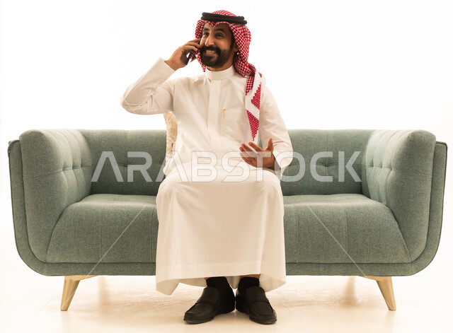 رجل سعودي يتحدث بالهاتف على أريكة خضراء