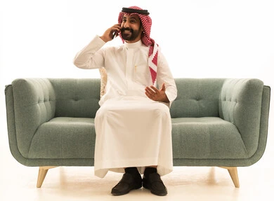 رجل سعودي يتحدث بالهاتف على أريكة خضراء