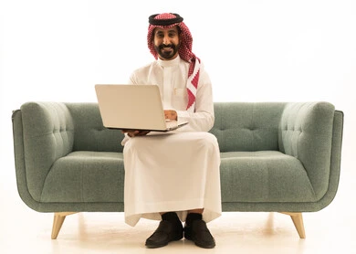 Saudi Man Using Laptop on Green Sofa White Background