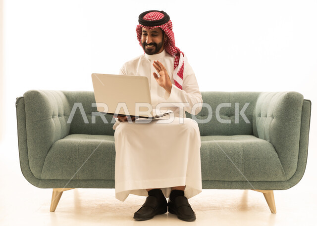 رجل سعودي يستخدم المحمول على الأريكة لمكالمة فيديو
