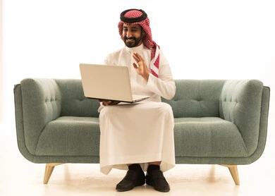رجل سعودي يستخدم المحمول على الأريكة لمكالمة فيديو