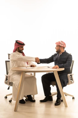 مصافحة رجل سعودي وكوردستاني على طاولة مكتب