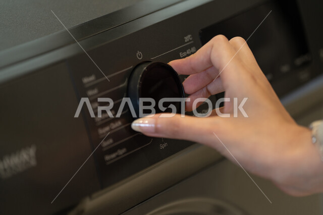امرأة تضبط إعدادات غسالة ملابس حديثة