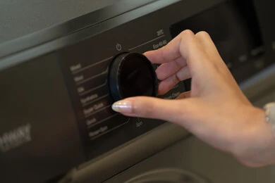 امرأة تضبط إعدادات غسالة ملابس حديثة