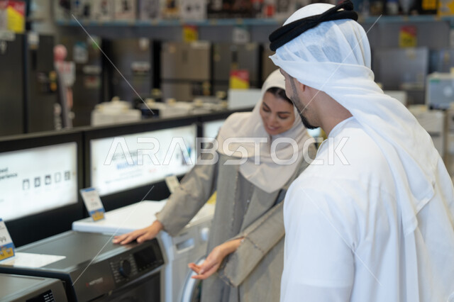 زوجين إماراتيين يتسوقان لشراء غسالة ملابس في متجر