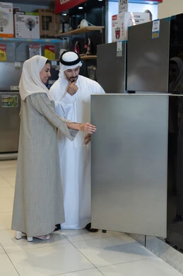 زوجان إماراتيان يتسوقان لشراء ثلاجة في متجر إلكترونيات
