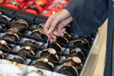 امرأة عربية بالعباءة تتسوق لشراء ساعة يد فاخرة في متجر