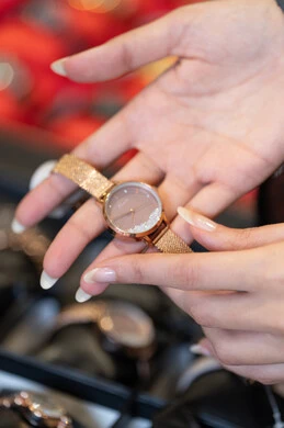 امرأة تمسك ساعة يد ذهبية في متجر مجوهرات