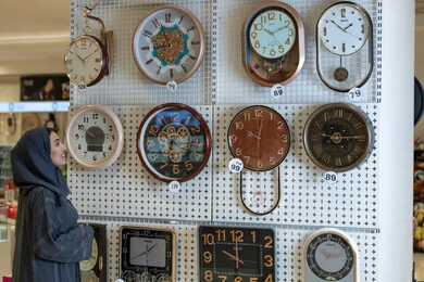 امرأة سعودية تتسوق وتختار ساعات حائط في متجر