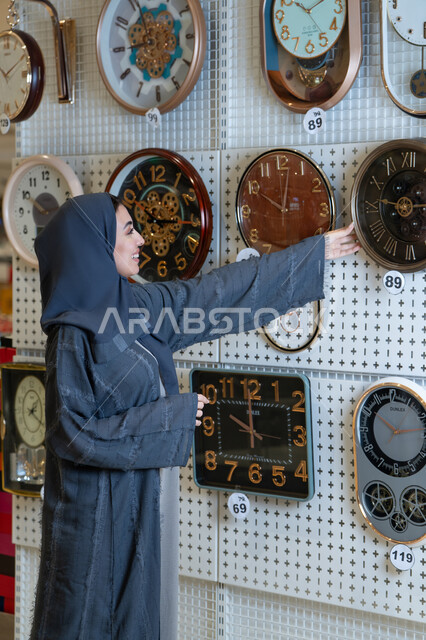 Saudi Woman Browsing Wall Clocks in Retail Store