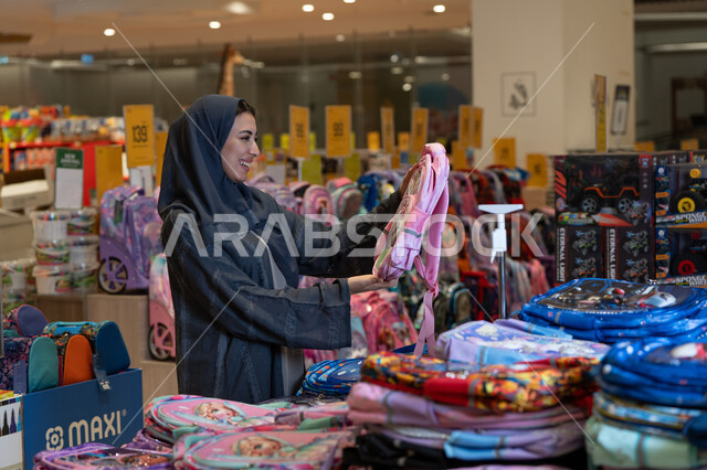 امرأة سعودية تتسوق حقائب مدرسية في متجر تجاري