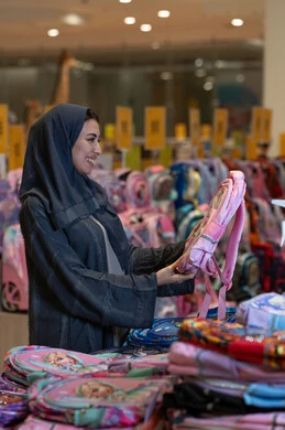 امرأة سعودية تشتري حقيبة مدرسية في متجر تجزئة