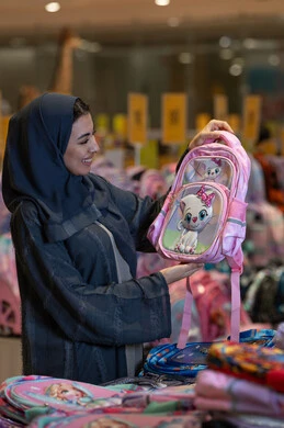 امرأة سعودية تتسوق لشراء حقيبة مدرسية في متجر
