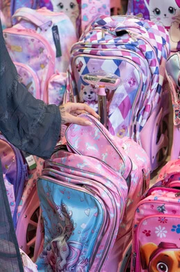 امرأة عربية تتسوق حقائب مدرسية وردية