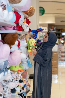 امرأة عربية بالعباءة تتسوق ألعاب أطفال في المتجر