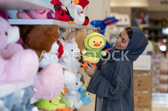 امرأة سعودية بالعباءة تتسوق في متجر دمى محشوة