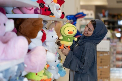 امرأة سعودية بالعباءة تتسوق في متجر دمى محشوة