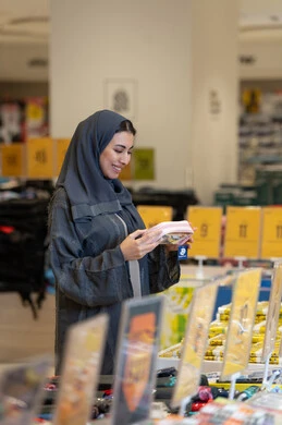 امرأة إماراتية بعباءة رمادية تتسوق في متجر تجزئة