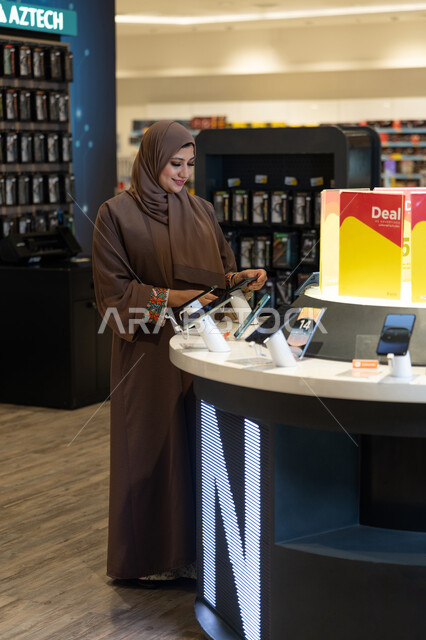 امرأة إماراتية تتسوق لشراء هاتف ذكي في متجر إلكترونيات